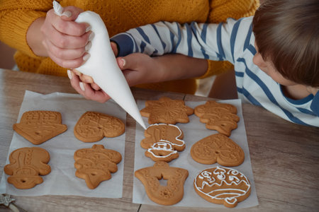 Mother and child decorating Christmas gingerbread cookies with icing sugar together