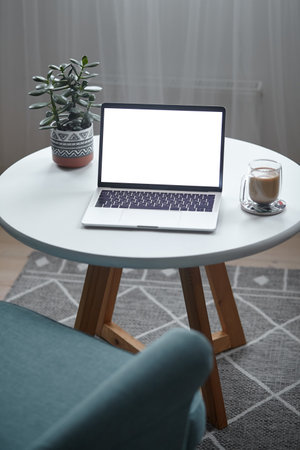 Laptop screen mockup on table with coffee cup and houseplant at home, no peopleの写真素材
