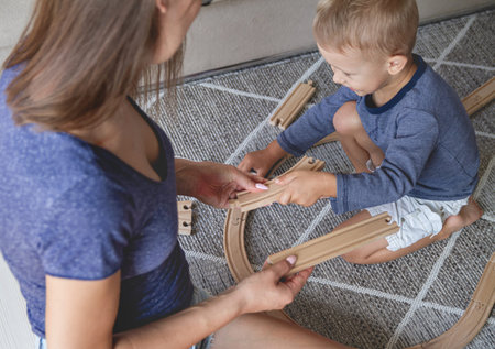 Little kid boy and his mother playing with railway