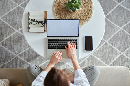 Mockup white screen laptop woman using computer sitting on sofa at home, top viewの写真素材