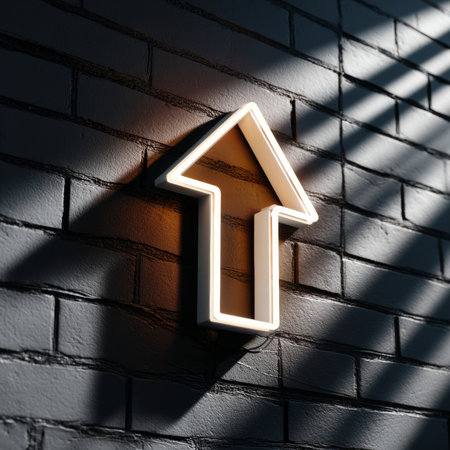 A glowing neon arrow pointing upwards on a brick wall, symbolizing progress or direction towards success.の素材