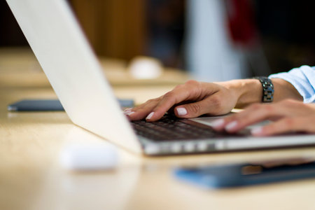 Woman hands typing on a laptop keyboard, close up