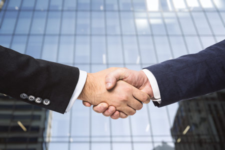 Two businessmen shake hands on the background of the exterior of an office building. Partnership conceptの写真素材