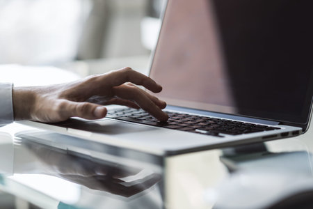 Businessman typing on a laptop, close up
