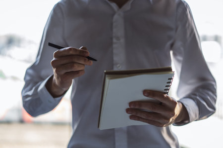 Businessman stands makes notes in a notebook. Closeup