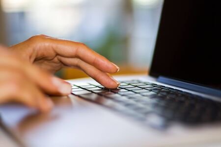 Woman types on a laptop keyboard at home, freelance concept, close upの写真素材