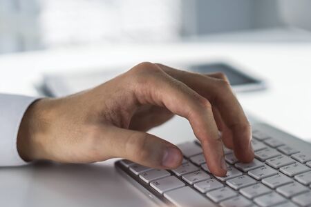 Man types on a white computer keyboard, close upの写真素材