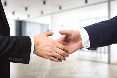 Two businessmen shake hands on the background of modern furnished office, deal concept, close upの写真素材