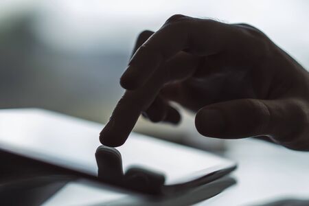 Male hand working with digital tablet in sunny office, business and technology concept. Close upの写真素材