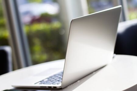 Close up of modern laptop on white table in sunny interior. Business and technology conceptの写真素材
