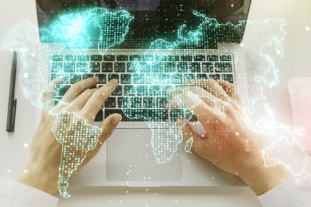 Double exposure of abstract digital world map and hand typing on laptop on background, big data and...