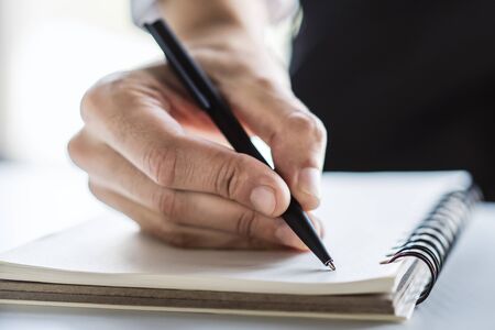 Man writes with a pen in diary in a sunny office, business and education concept. Close upの写真素材