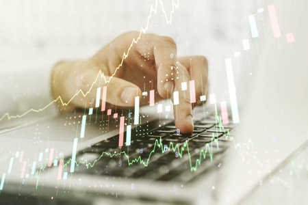 Abstract creative financial graph with hand typing on laptop on background, forex and investment...