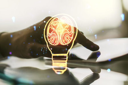 Creative light bulb with human brain hologram and hand working with a digital tablet on background,...