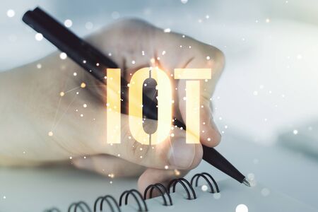 Creative IOT hologram with man hand writing in notepad on background, internet of things concept. Multiexposureの写真素材