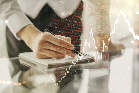 Multi exposure of abstract financial diagram with world map and with man hand writing in notepad on...