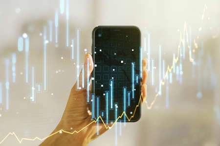 Abstract creative financial graph and hand with phone on background, forex and investment concept. Multiexposureの写真素材
