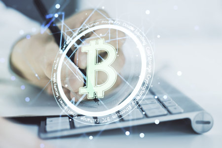 Double exposure of creative Bitcoin symbol with hand writing in notebook on background with laptop....