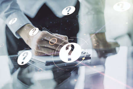 Creative abstract question mark hologram and man hand writing in diary on background, future technology concept. Multi exposureの写真素材