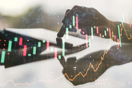 Multi exposure of abstract financial graph with world map and hand working with a digital tablet on background, financial and trading conceptの写真素材
