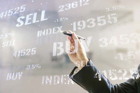 Double exposure of man hand with pen working with virtual creative financial diagram on blurred office background, banking and accounting conceptの写真素材