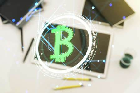 Double exposure of creative Bitcoin symbol hologram and modern digital tablet on background. Mining and blockchain conceptの写真素材