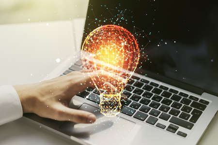 Double exposure of creative light bulb hologram with hands typing on laptop on background, research and development conceptの写真素材