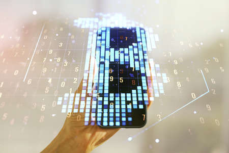 Double exposure of creative Bitcoin symbol hologram and hand with cellphone on background. Mining and blockchain conceptの写真素材