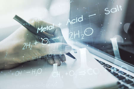 Double exposure of creative chemistry concept with hand writing in notebook on background with laptop, research and development conceptの写真素材