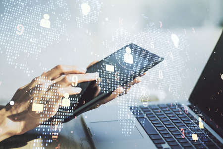 Double exposure of social network icons concept with world map and hand working with a digital tablet on background. Networking conceptの写真素材