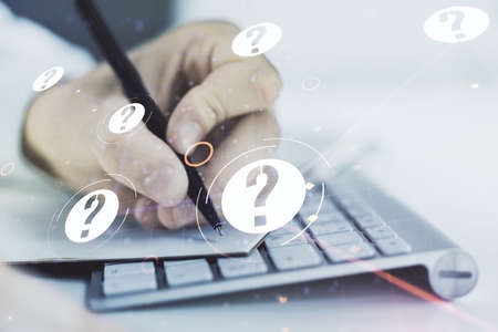 Creative abstract question mark sketch and hand writing in notepad on background with laptop, FAQ and research concept. Double exposureの写真素材