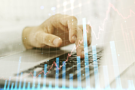 Abstract creative financial graph with hand typing on laptop on background, forex and investment...