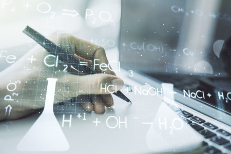 Double exposure of creative chemistry concept with hand writing in notebook on background with laptop, research and development conceptの写真素材