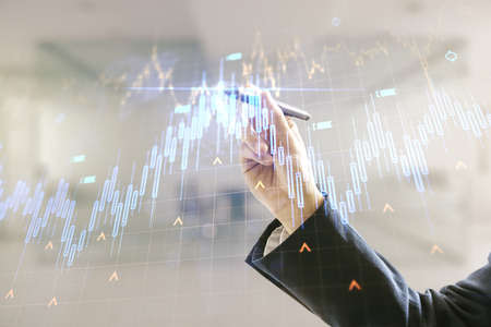 Double exposure of man hand with pen working with abstract creative financial chart and world map on blurred office background, research and strategy conceptの写真素材
