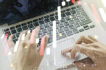Abstract creative financial graph with world map and with hands typing on laptop on background,...