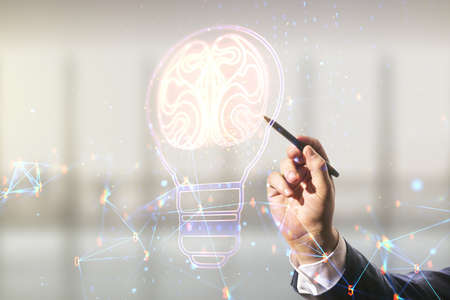 Man hand with pen draws abstract virtual creative light bulb with human brain hologram on blurred office background, artificial Intelligence and neural networks concept. Multiexposureの写真素材