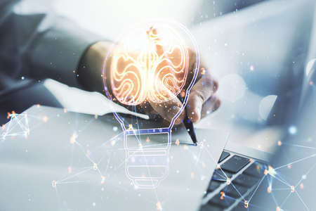 Creative idea concept with light bulb and human brain illustration and with hand writing in notebook on background with laptop. Neural networks and machine learning concept. Multiexposureの写真素材