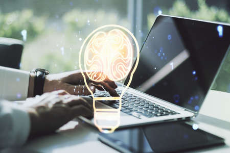 Creative light bulb with human brain hologram and with hands typing on computer keyboard on background, artificial Intelligence and neural networks concept. Multiexposureの写真素材