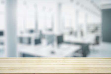 Empty wooden table top with light sunny furnished office on background, mock upの写真素材