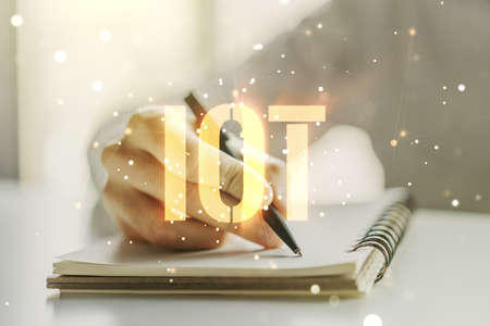Creative IOT hologram with man hand writing in notepad on background, internet of things concept. Multiexposureの写真素材