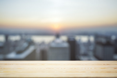 Empty wooden tabletop with beautiful blurry skyscrapers in the afternoon on background, mock up