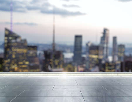 Empty concrete rooftop on the background of a beautiful blurry New York city skyline at evening, mock upの写真素材