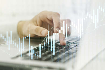 Abstract creative financial graph with hand typing on laptop on background, financial and trading concept. Multiexposureの写真素材