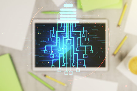 Creative light bulb illustration with microcircuit and modern digital tablet on desktop on...