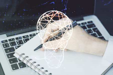 Creative light bulb hologram with hand writing in notepad on background with laptop, idea concept....