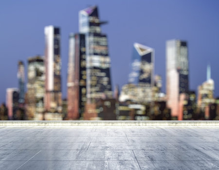 Empty concrete dirty rooftop on the background of a beautiful blurry NY city skyline at night, mock...