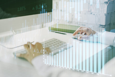 Abstract creative financial graph with hand typing on laptop on background, forex and investment...