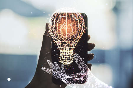 Creative light bulb illustration and hand with mobile phone on background, future technology concept. Multi-exposureの写真素材