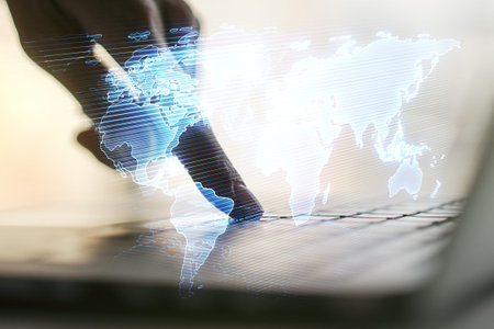 Abstract creative world map and hands typing on laptop on background, international trading concept....