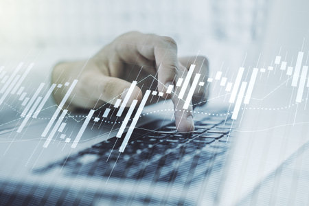 Abstract creative financial graph with hand typing on laptop on background, forex and investment...